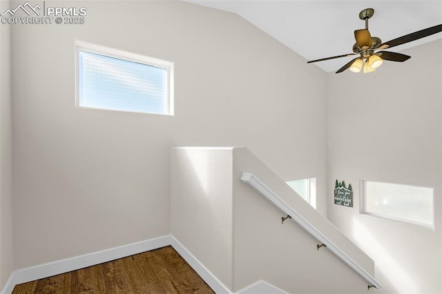 hall with an upstairs landing, baseboards, wood finished floors, and vaulted ceiling