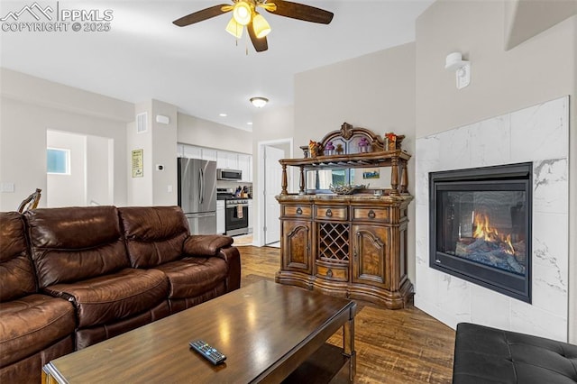 living area featuring visible vents, dark wood-type flooring, ceiling fan, and a premium fireplace