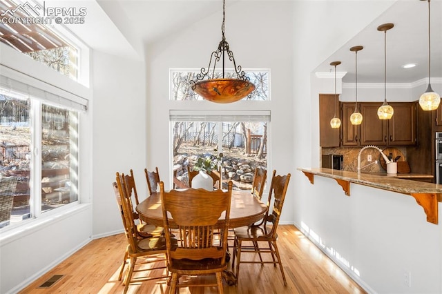 dining room featuring light wood-type flooring, a wealth of natural light, visible vents, and baseboards