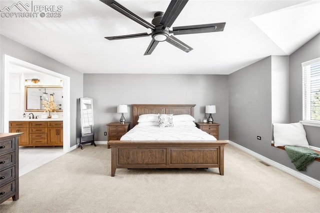 bedroom with baseboards, a ceiling fan, light colored carpet, ensuite bathroom, and a sink