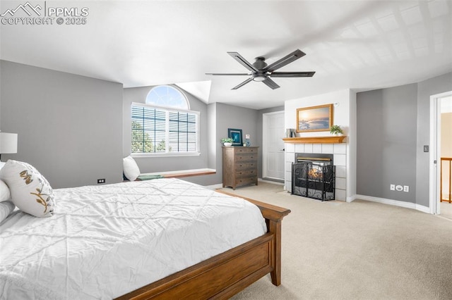 bedroom with carpet, baseboards, vaulted ceiling, and a tile fireplace