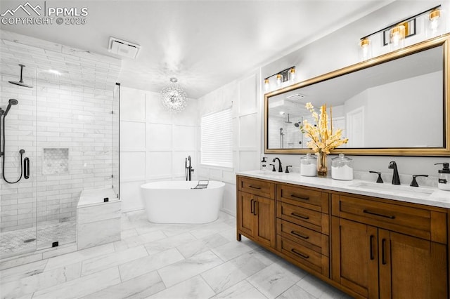 bathroom featuring marble finish floor, double vanity, a sink, a shower stall, and a freestanding tub