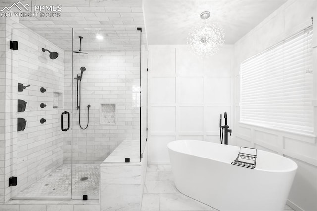 full bath with a stall shower, marble finish floor, a decorative wall, and a freestanding bath