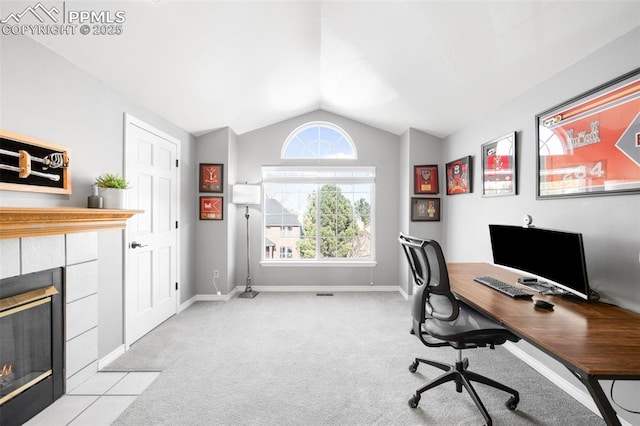 home office with light carpet, baseboards, a tiled fireplace, and lofted ceiling