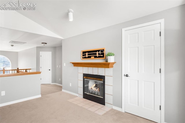 unfurnished living room featuring lofted ceiling, carpet flooring, visible vents, baseboards, and a tiled fireplace