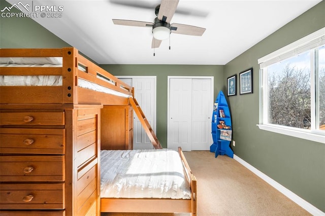 carpeted bedroom with ceiling fan, baseboards, and multiple closets