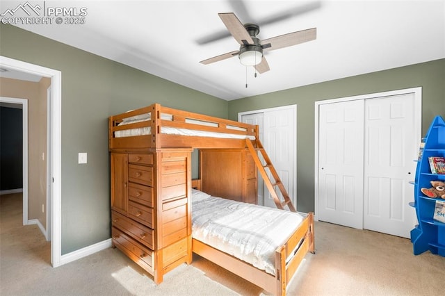 bedroom with baseboards, ceiling fan, light colored carpet, and multiple closets