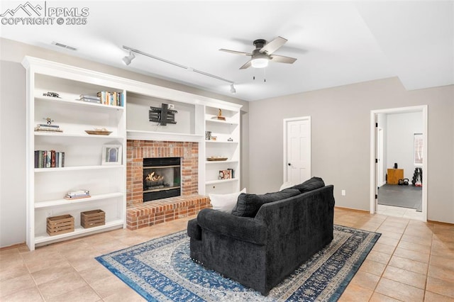 living room featuring light tile patterned floors, built in shelves, visible vents, a ceiling fan, and a brick fireplace