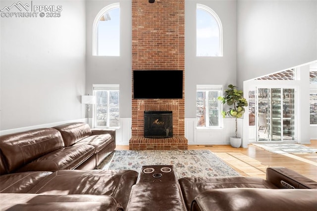 living room featuring a fireplace, a towering ceiling, and wood finished floors