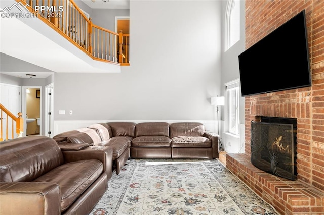 living area featuring a fireplace, stairway, and a high ceiling