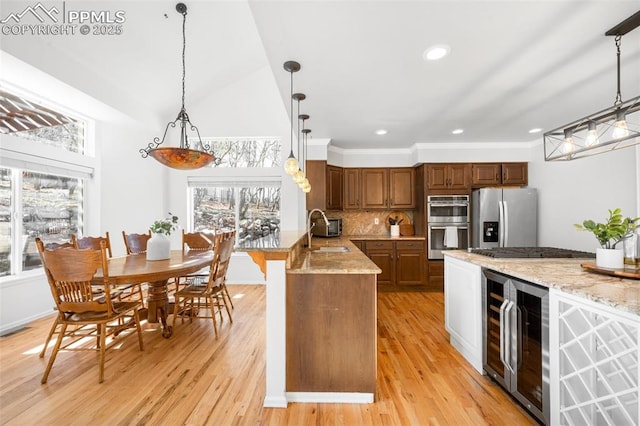 kitchen with decorative backsplash, wine cooler, appliances with stainless steel finishes, a peninsula, and a sink