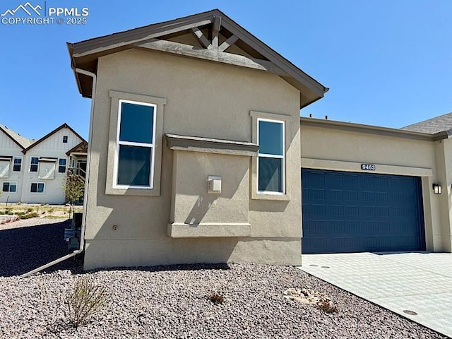 9463 Jollity Pt, Colorado Springs, CO 80924 - view of property exterior with driveway, an attached garage, and stucco siding