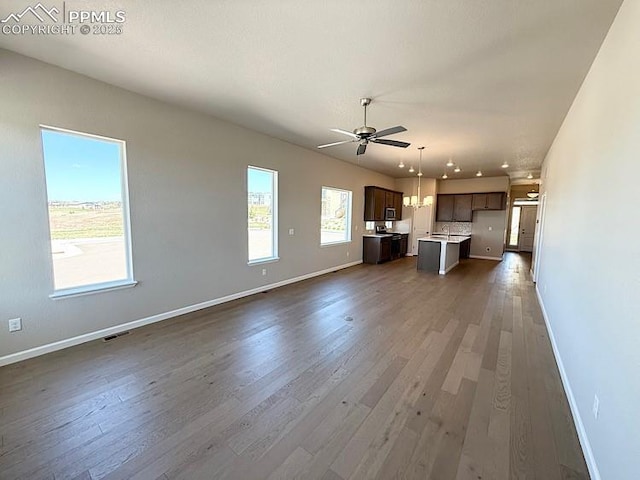 9463 Jollity Pt, Colorado Springs, CO 80924 - unfurnished living room with baseboards, a ceiling fan, and dark wood-type flooring