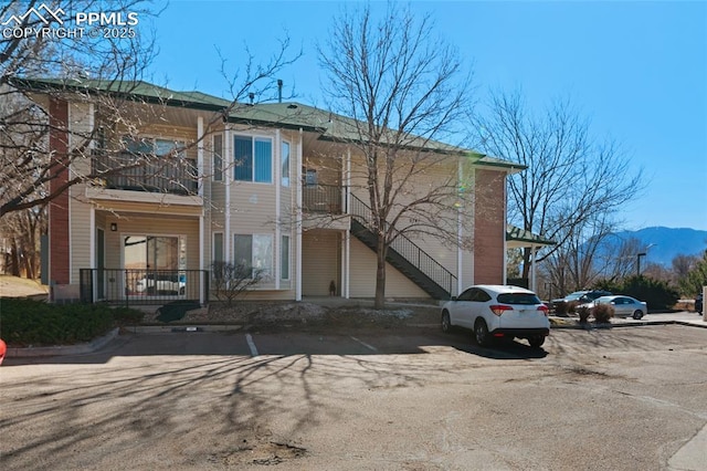 view of front of house with a mountain view, a balcony, and uncovered parking