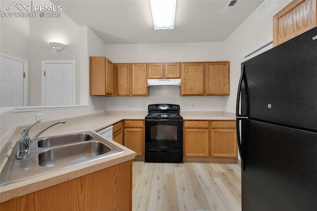 kitchen with visible vents, black appliances, under cabinet range hood, a sink, and light wood finished floors