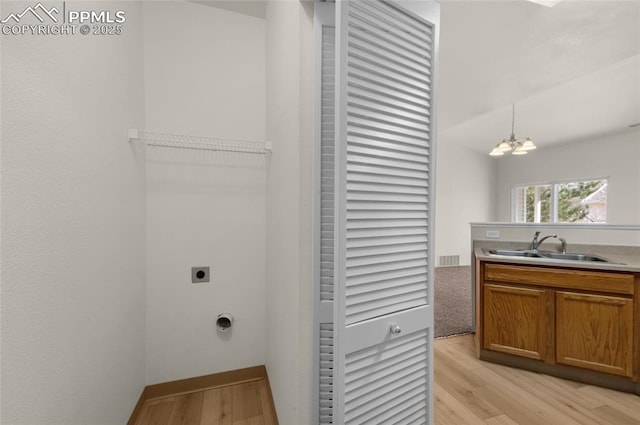 washroom with light wood finished floors, laundry area, a notable chandelier, electric dryer hookup, and a sink