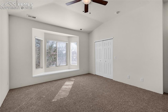 spare room featuring lofted ceiling, a ceiling fan, visible vents, and carpet floors