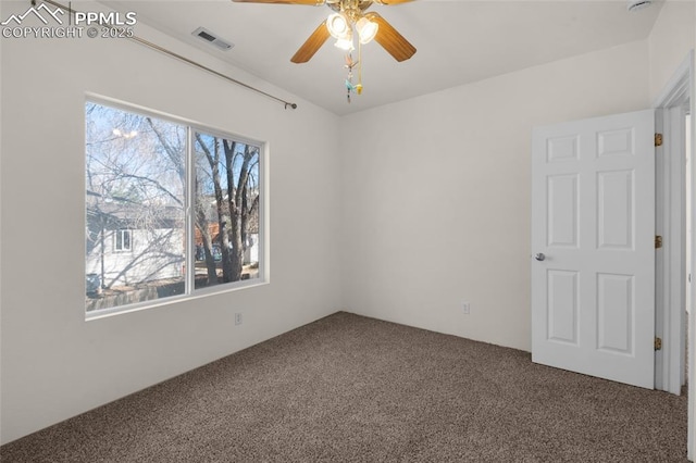 carpeted spare room featuring visible vents and ceiling fan