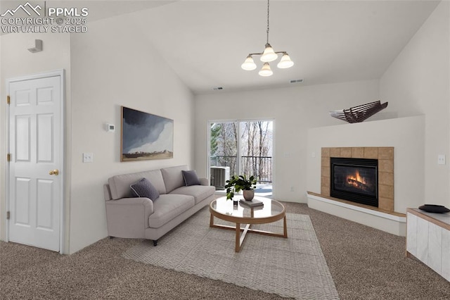 living room with visible vents, carpet floors, lofted ceiling, and a tiled fireplace