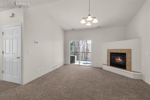 unfurnished living room featuring visible vents, lofted ceiling, carpet, and a tiled fireplace