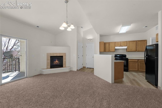 kitchen with under cabinet range hood, lofted ceiling, light carpet, brown cabinets, and black appliances