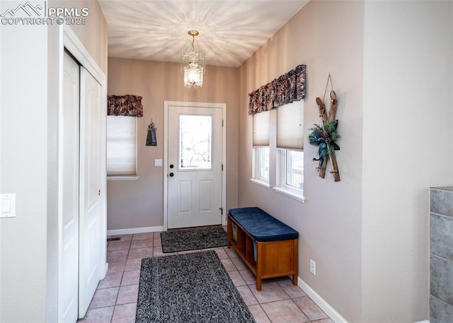 doorway to outside featuring light tile patterned floors, baseboards, and a notable chandelier