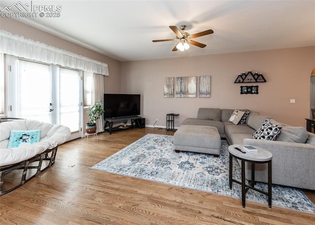 living room with a ceiling fan, baseboards, and wood finished floors