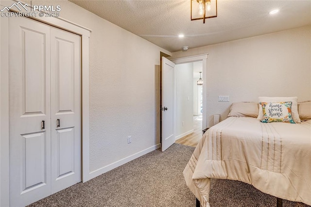 bedroom with baseboards, a textured ceiling, and light colored carpet