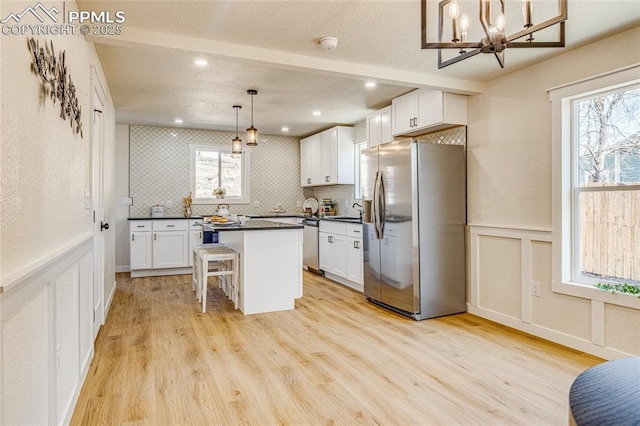 kitchen with tasteful backsplash, dark countertops, appliances with stainless steel finishes, light wood-style floors, and a sink