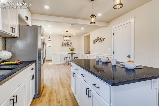 kitchen with light wood-style floors, dark countertops, and white cabinetry