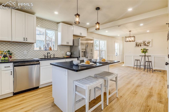 kitchen with appliances with stainless steel finishes, dark countertops, a sink, and a breakfast bar area