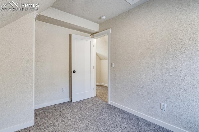 carpeted spare room with a textured wall and baseboards