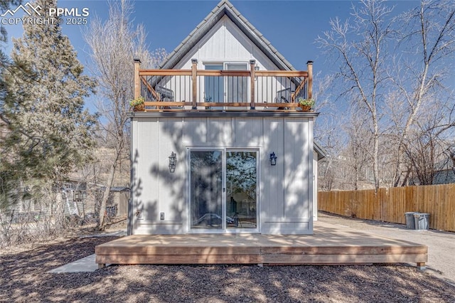 rear view of house featuring a balcony, fence, and a deck