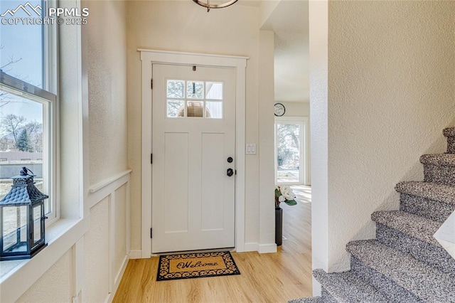 entrance foyer with light wood-style flooring, a textured wall, and stairway