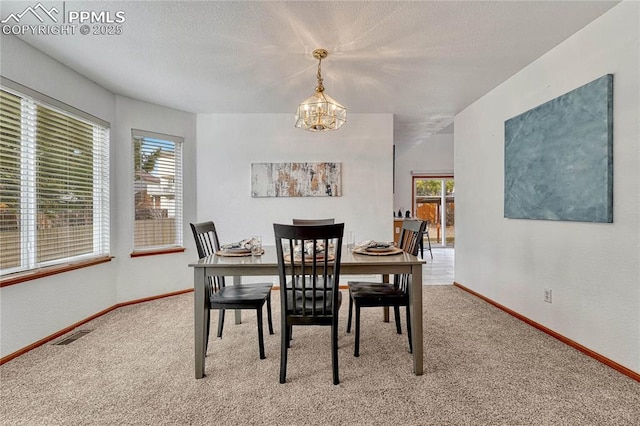 carpeted dining room featuring baseboards, a textured ceiling, visible vents, and an inviting chandelier