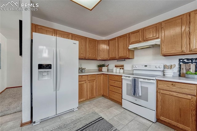 kitchen with a textured ceiling, under cabinet range hood, white appliances, light countertops, and brown cabinets