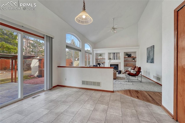 interior space with ceiling fan, visible vents, and a glass covered fireplace