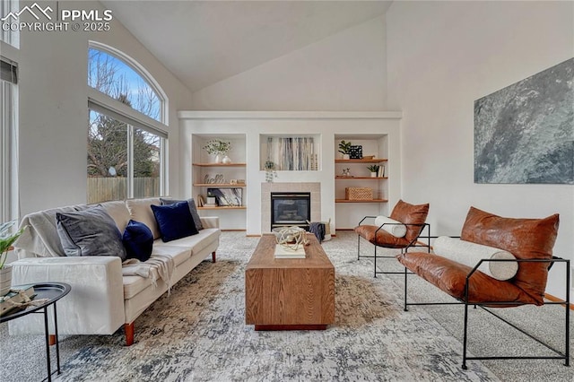 living area with built in shelves, a fireplace, and high vaulted ceiling