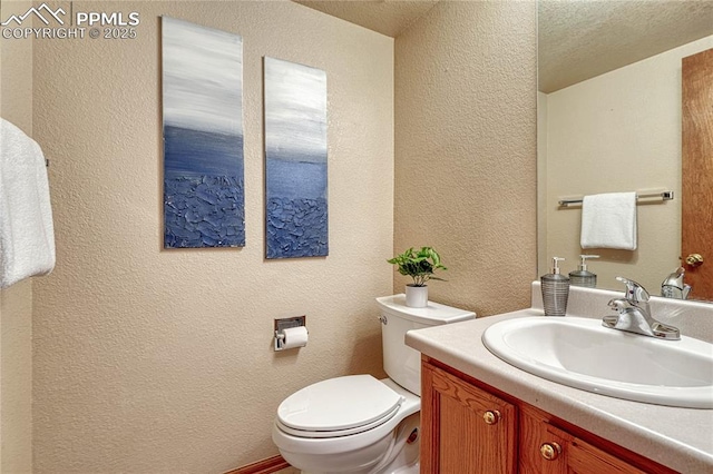 half bathroom featuring a textured wall, vanity, and toilet