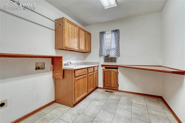 laundry room featuring hookup for an electric dryer, a sink, visible vents, baseboards, and cabinet space