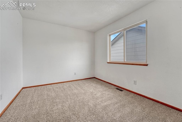 spare room featuring a textured ceiling, carpet flooring, visible vents, and baseboards