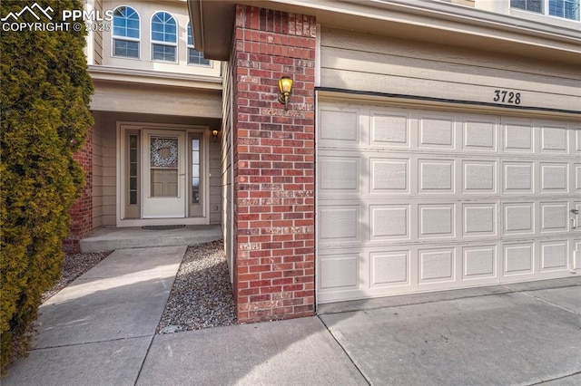 property entrance featuring a garage, concrete driveway, and brick siding