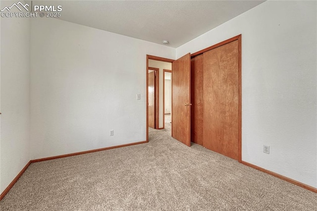 unfurnished room featuring a textured ceiling, carpet flooring, and baseboards