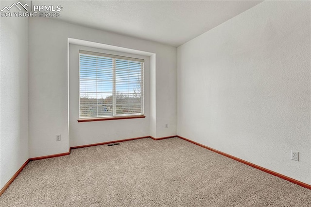 empty room featuring carpet floors, visible vents, and baseboards