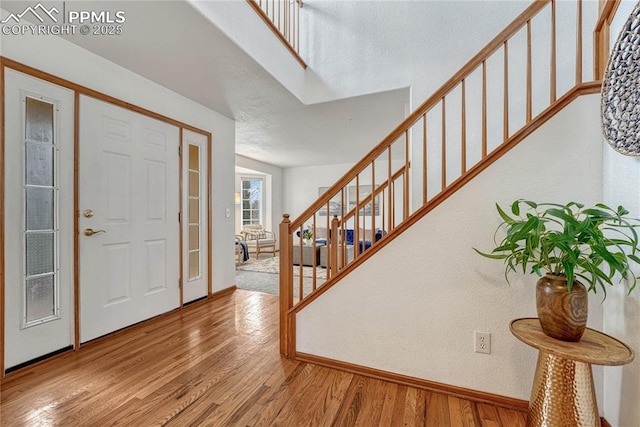 entryway with stairs, baseboards, and wood finished floors