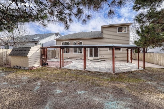 back of property featuring a fenced backyard, a storage shed, an outdoor structure, roof with shingles, and a patio area