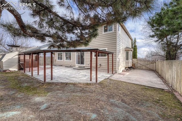 rear view of property featuring a patio area, a gate, and fence