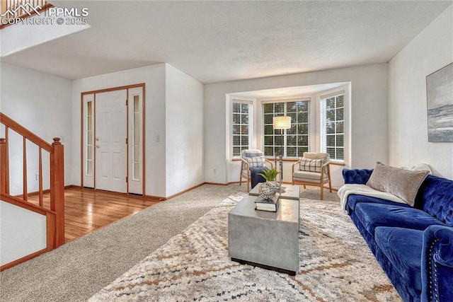 carpeted living area with baseboards, stairway, and a textured ceiling