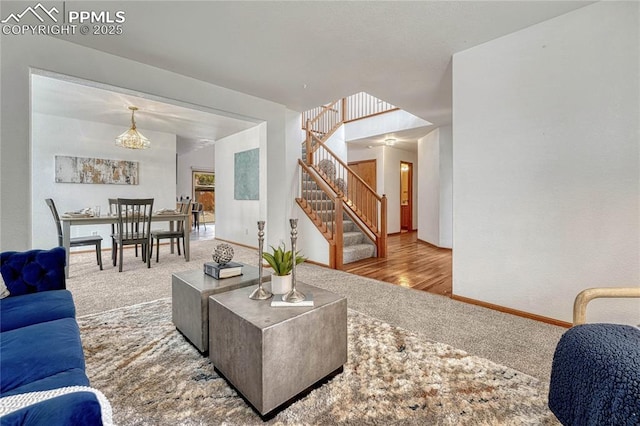 carpeted living room featuring stairs and baseboards