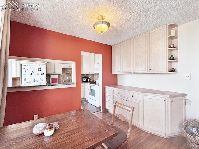 unfurnished dining area featuring a textured ceiling and wood finished floors